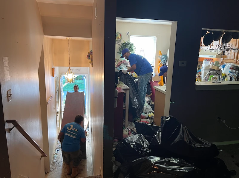JunkDoctors NJ crew bagging trash and safely carrying heavy furniture down stairs during a messy residential foreclosure cleanout.
