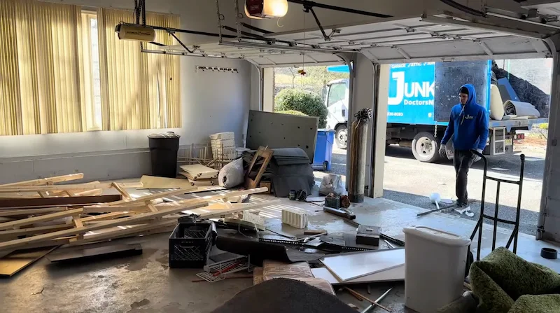 Professional garage cleanout service in New Jersey by Junk Doctors, featuring a team member loading debris into a junk removal truck.