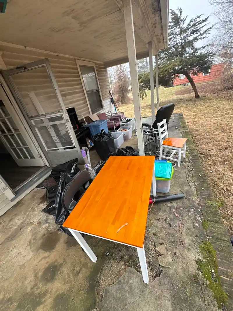 A porch at a New Jersey foreclosure property piled with household junk and old furniture before being hauled away by JunkDoctors.
