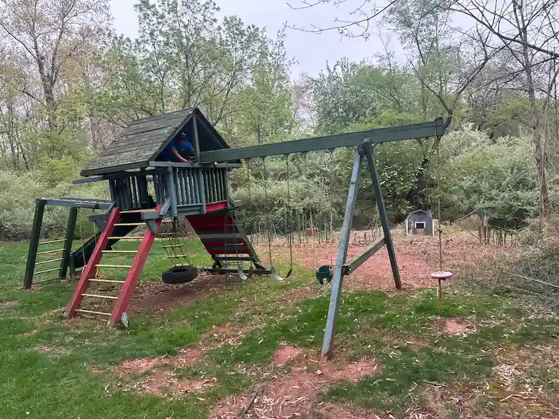 JunkDoctors team member dismantling a large wooden playset and swing set in a North Jersey backyard.